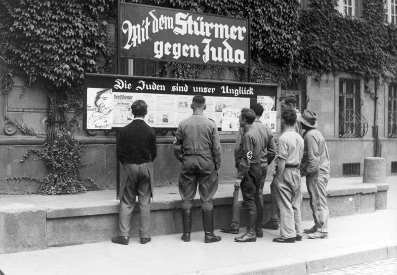 Tygodnik „Der Stürmer” był jednym z głównych narzędzi nazistów w szerzeniu antysemickich haseł. Na zdjęciu z 1933 roku mieszkańcy Wormacji czytają „Stürmera” (źródło: Bundesarchiv; lic. CC ASA 3.0).