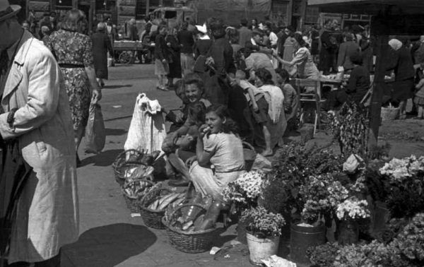 Kobiety handlujące kwiatami i pieczywem na jednej z warszawskich ulic. Zdjęcie pochodzi z książki "Okupacja od kuchni".