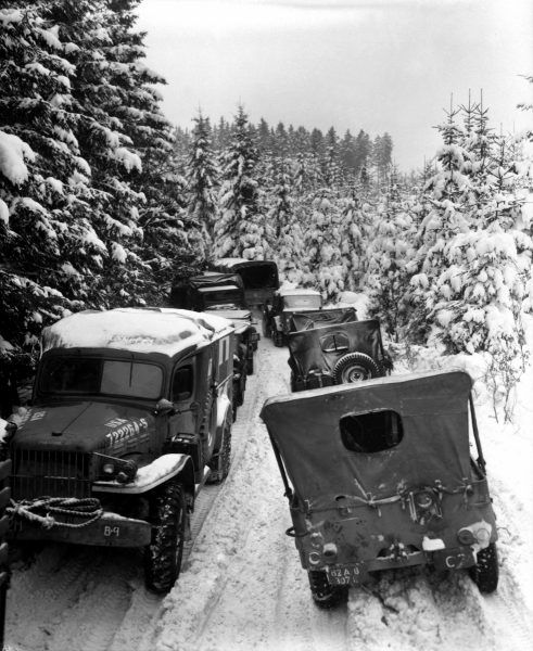 Ciężarówki i samochody 87 Dywizji Piechoty USA na leśnej drodze w pobliżu w Belgii (fot. Norbuth, ze zbiorów National Archives and Records Administration, domena publiczna).