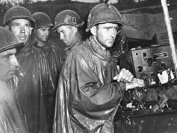 Amerykańscy żołnierze na Okinawie słuchają przez radio informacji o zakończeniu wojny w Europie, 8 maja 1945 r. (fot. U.S. military or Department of Defense, domena publiczna).