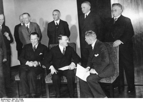 W 1933 roku Hitler z polityka wiecowego musiał przedzierzgnąć się w gabinetowego. Jednak wcale nie chciał zrezygnować dla władzy ze swobody robienia, czego chce. Nawet podczas pozowania do zdjęcia ze swym świeżo sformowanym gabinetem nie mógł się powstrzymać od gardłowania z wicekanclerzem von Papenem (Bundesarchiv, Bild 102-15348 / CC-BY-SA 3.0).