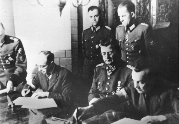 Podpisanie „Układu o zaprzestaniu działań wojennych w Warszawie”, 3 października 1944 roku. W środku siedzi generał von dem Bach, a obok niego dwóch powstańców: po lewej pułkownik Kazimierz Iranek-Osmecki „Heller”, po prawej podpułkownik Zygmunt Dobrowolski „Zyndram”.