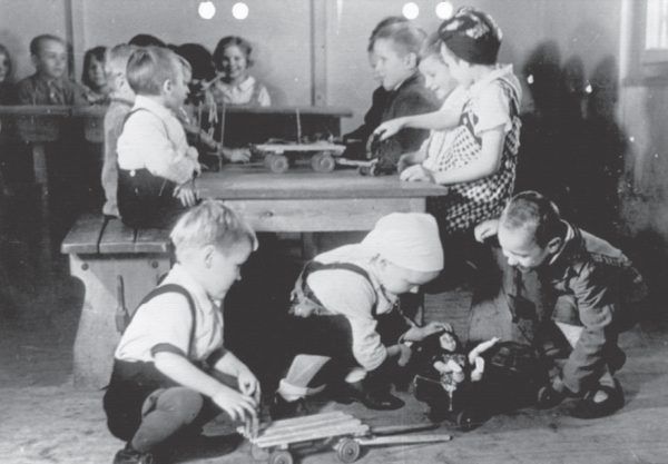 Propagandowe zdjęcie pokazujące, jak dobrze miało się żyć dzieciom robotnic przymusowych w specjalnych ośrodkach. Ilustracja i podpis z książki "Teraz jesteście Niemcami. Wstrząsające losy zrabowanych polskich dzieci".